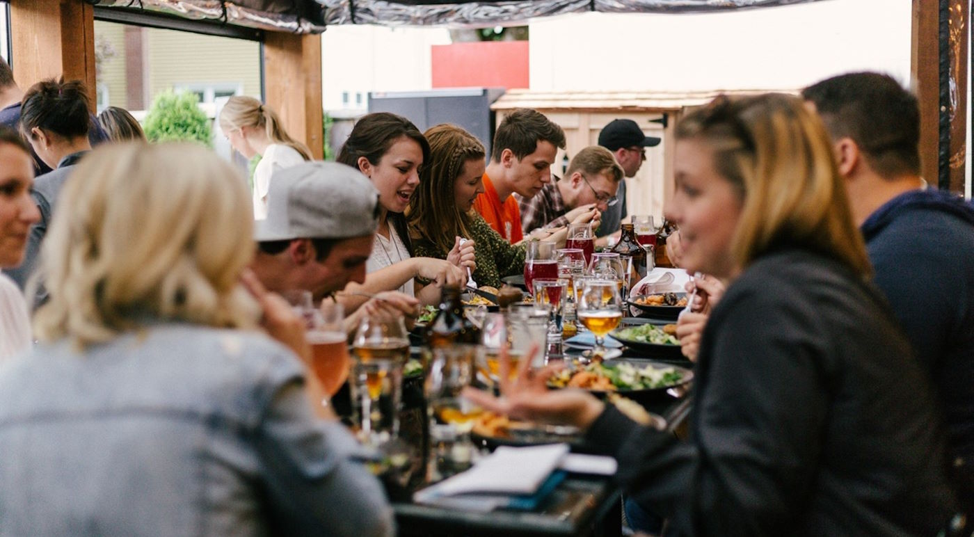 people enjoying food and drinks at the table